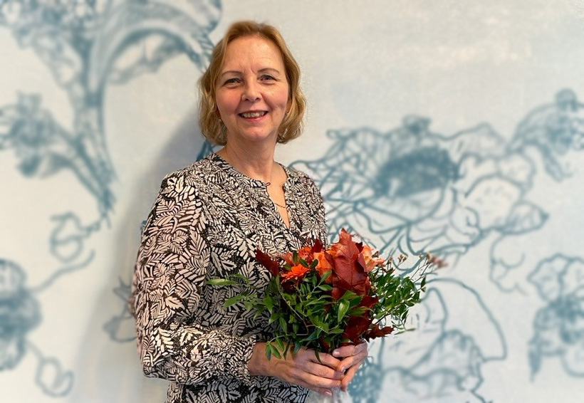 Mirja Mustasilta kädessään eläkkeelle jäämisen kunniaksi annettu kaunis kukkakimppu